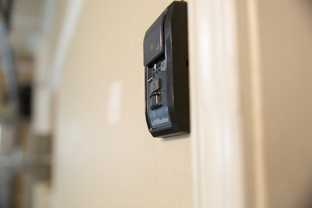 A black remote control is hanging on a white wall.