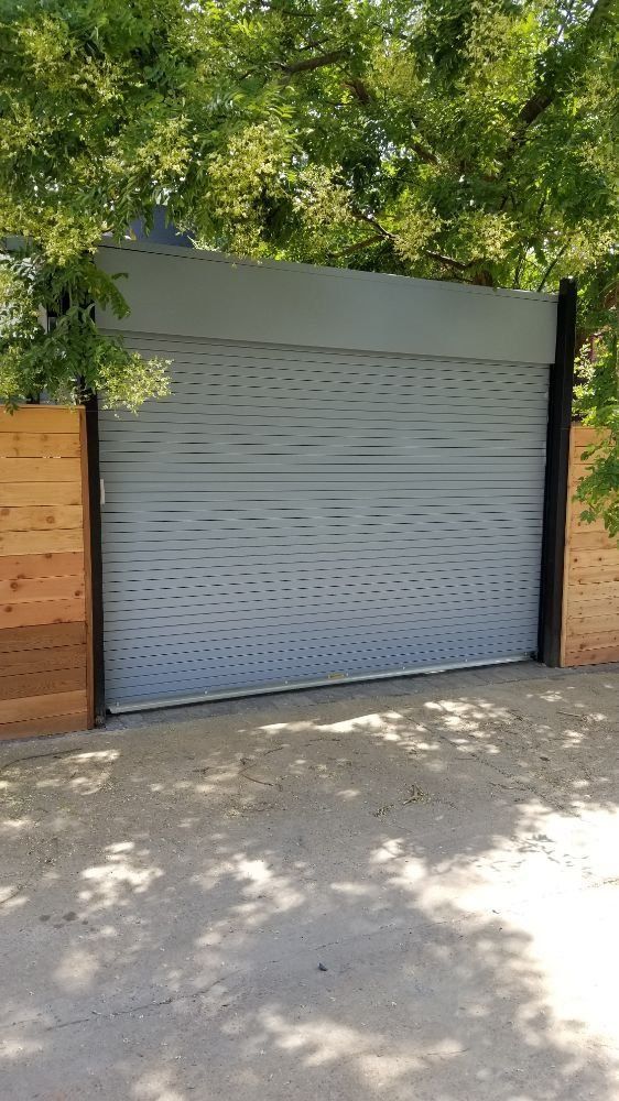 A white garage door is sitting next to a wooden fence.