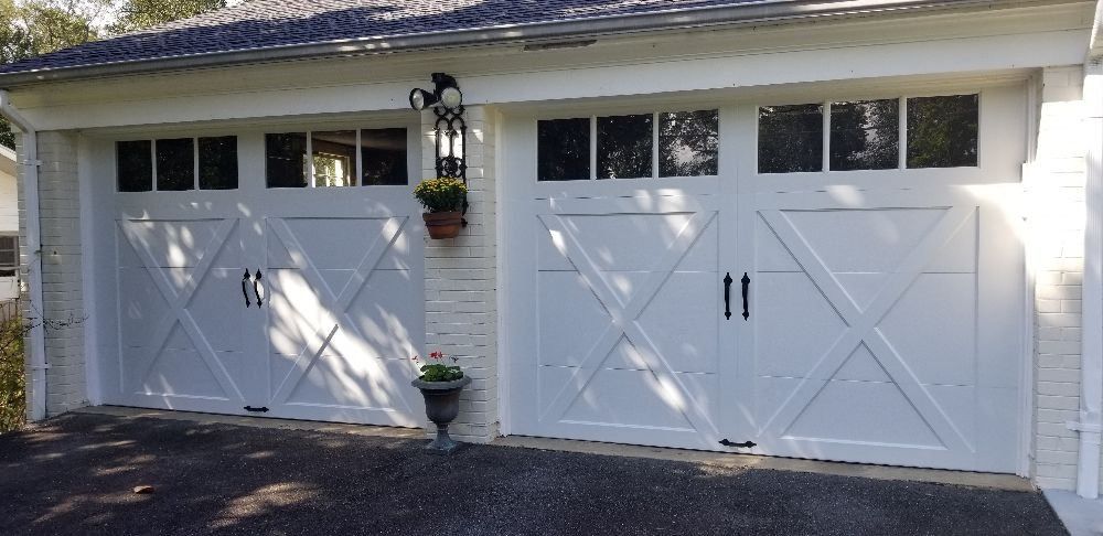 A pair of white garage doors are sitting next to each other on the side of a house.