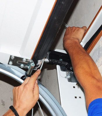 A man is fixing a garage door with a wrench