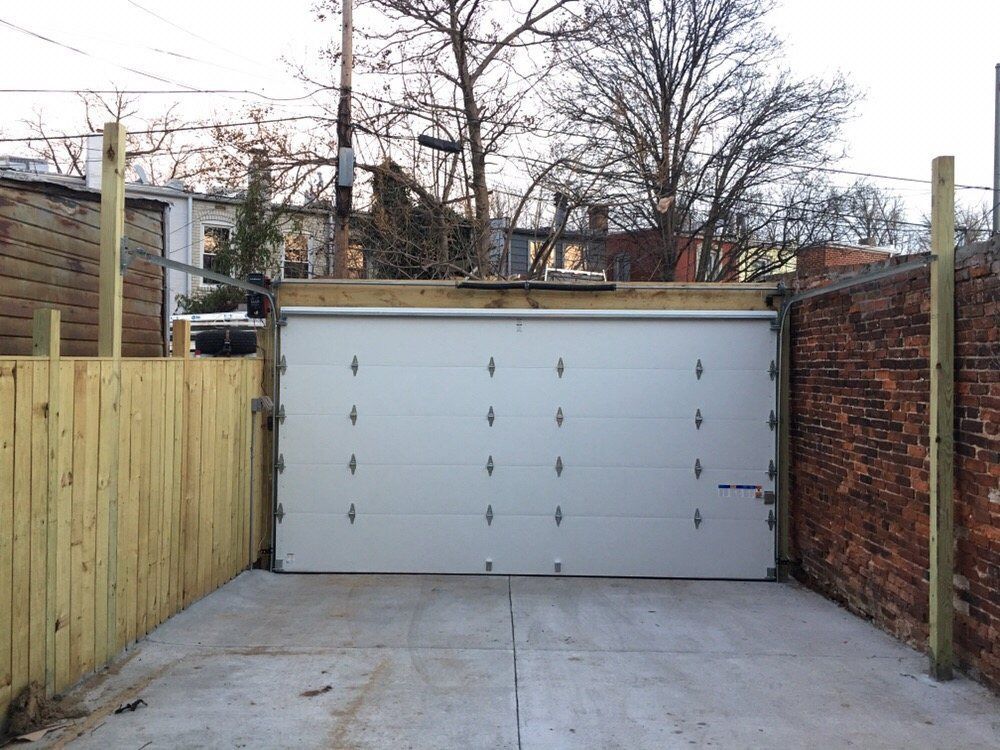 A white garage door with a wooden fence around it