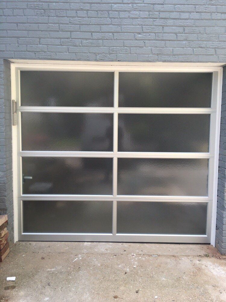 A garage door with a frosted glass door is sitting in front of a brick wall.