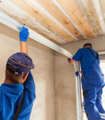 Two men are working on a garage door.