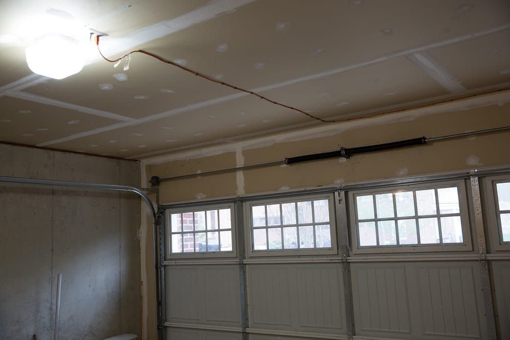 A garage with a garage door open and a light on the ceiling.